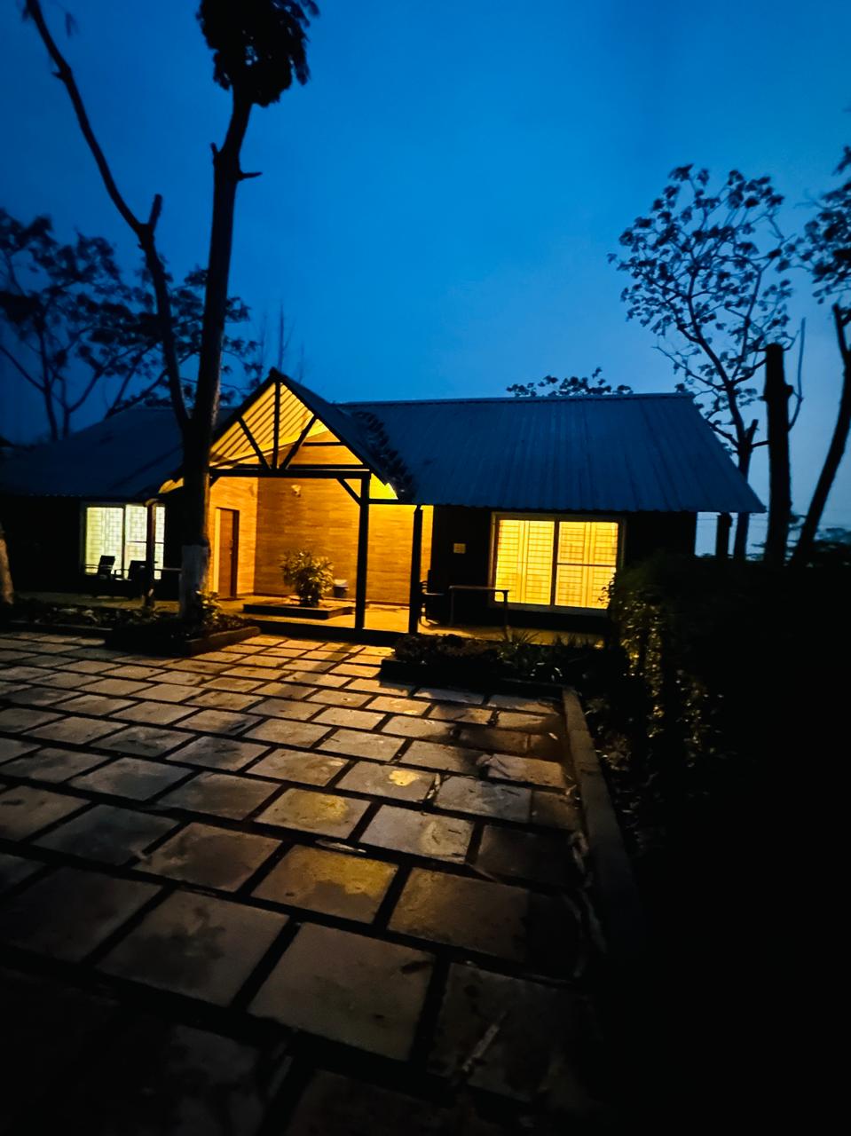 Cottage exterior lit up at dusk over flagstone courtyard