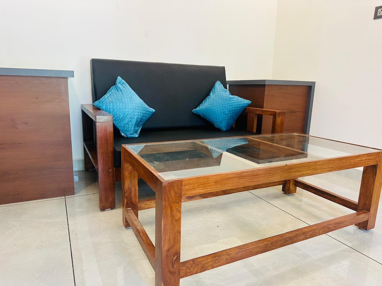 Wooden lounge sofa with teal cushions and coffee table