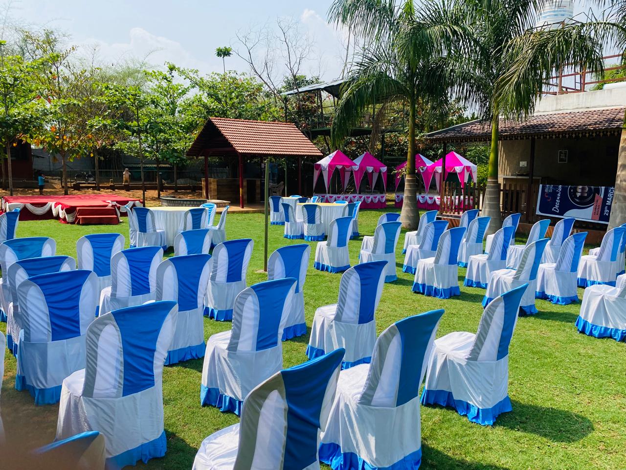 Outdoor event setup with blue and white chairs and pink pavilion tents